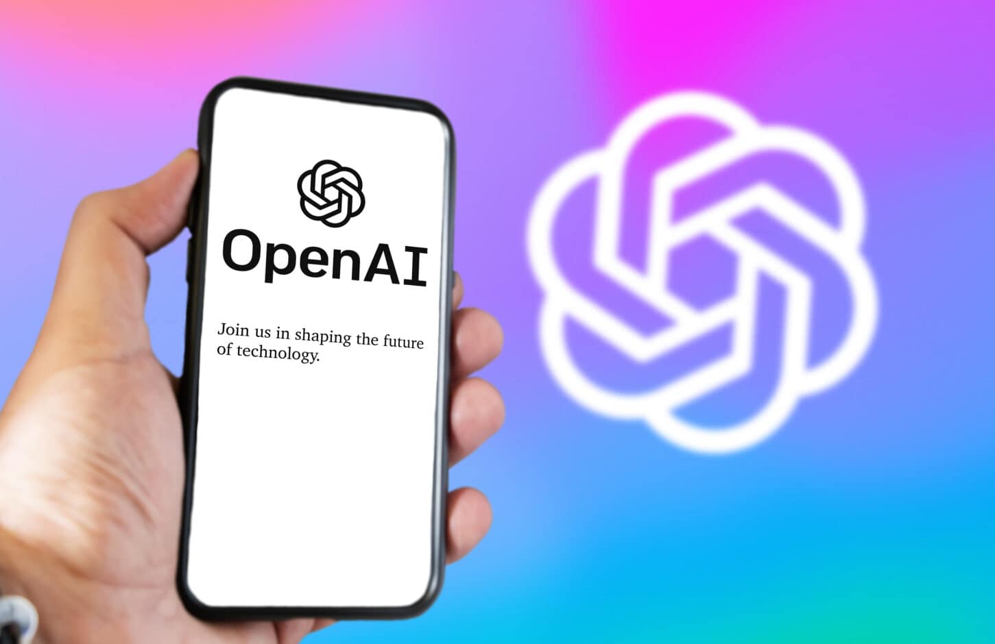 San Francisco US, Dec 2022: A hand holding a phone with the OpenAI website on the screen. Colorful background with blurred logo. OpenAI is a non-profit artificial intelligence research organization.